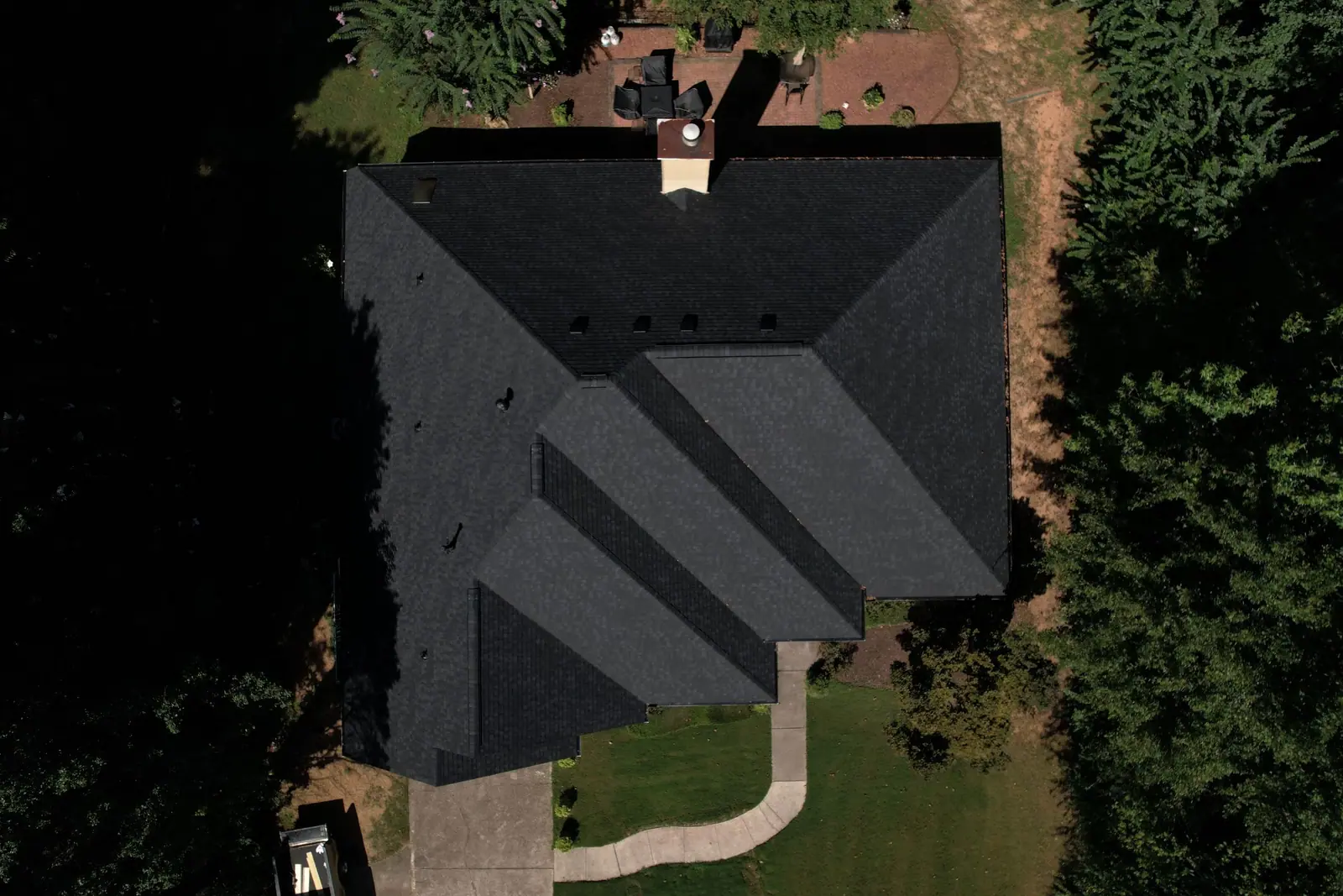 New black shingle roof on a home surrounded by woods, finished by Dryco Roofing