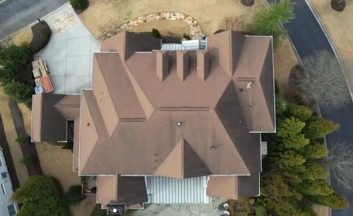 Drone view from above of a large home with a faded brown shingle roof, before Dryco Roofing replaced it