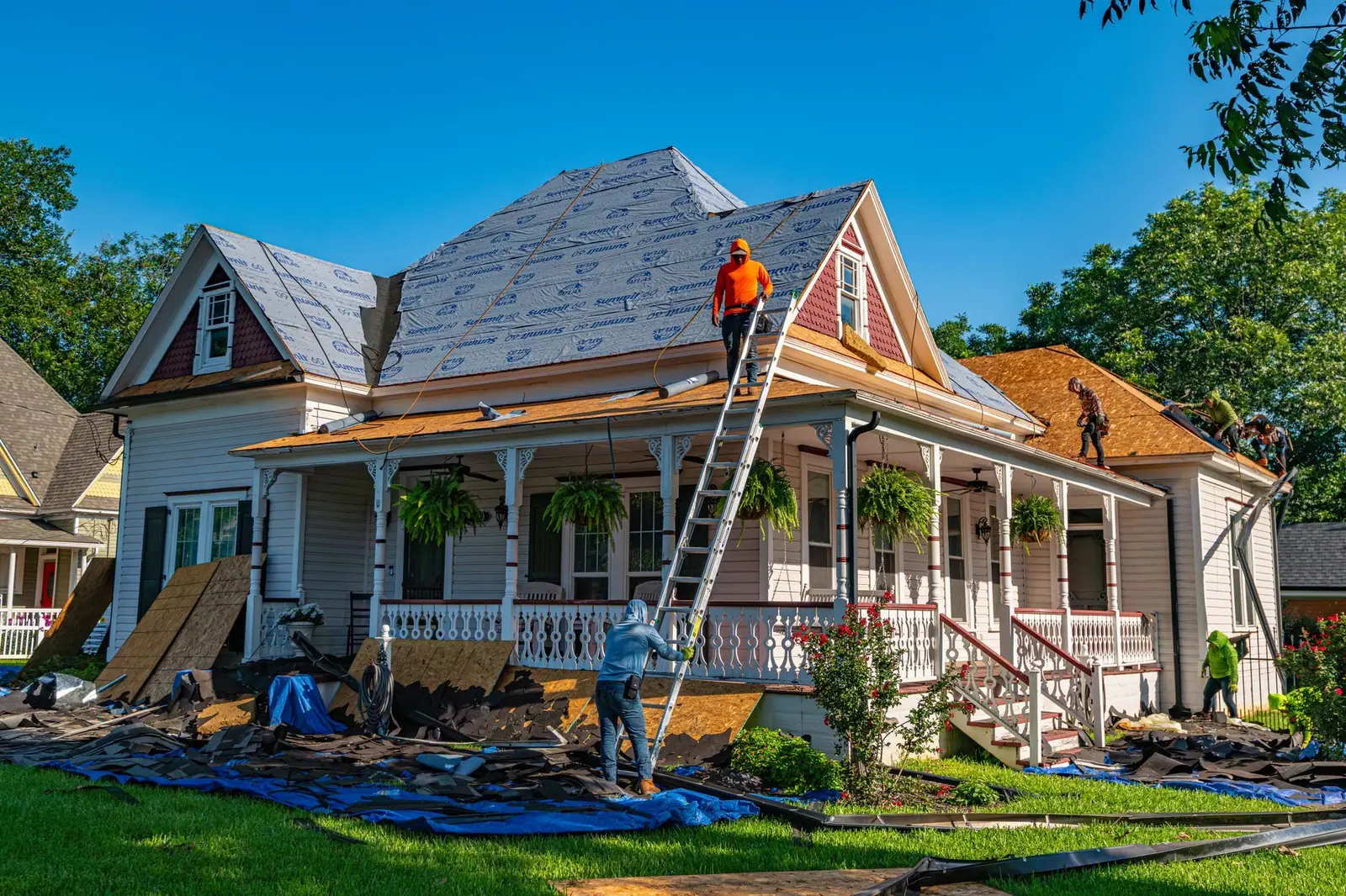 Roofing crew re-roofing a Victorian home with new decking and synthetic underlayment (representative photo)