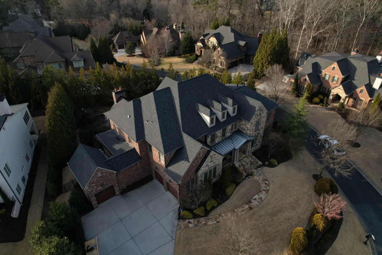 Stone and brick home with a new grey shingle roof and dormers by Dryco Roofing